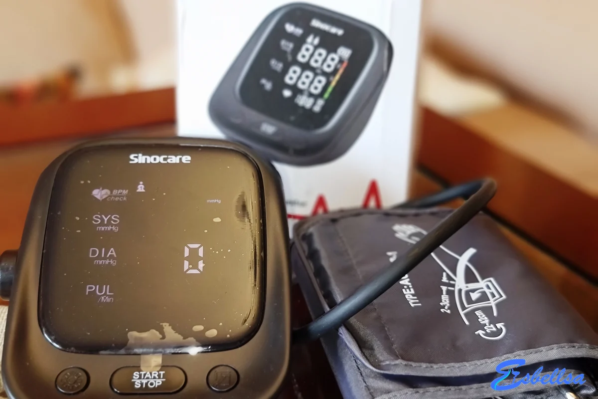 el manguito de tela del sinocare aes-u181 con su guía de colocación impresa, junto al aparato negro