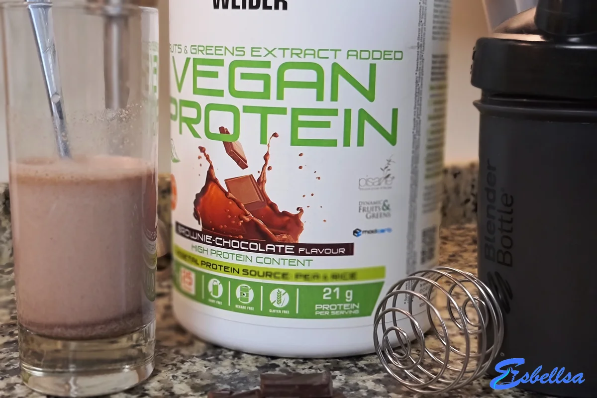 el batido de weider vegan protein brownie chocolate junto al bote y el shaker