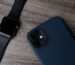 Reloj de correa negra junto a un móvil con funda azul sobre madera