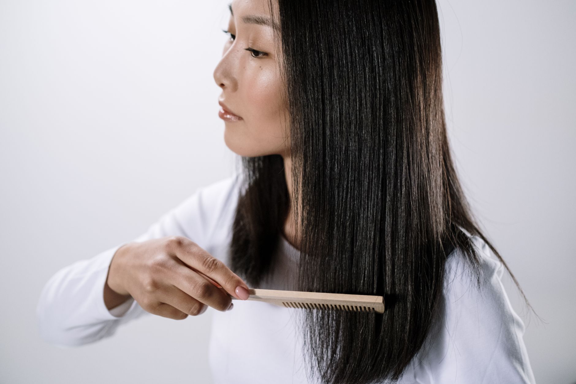 Persona peinándose el pelo largo con un peine de madera